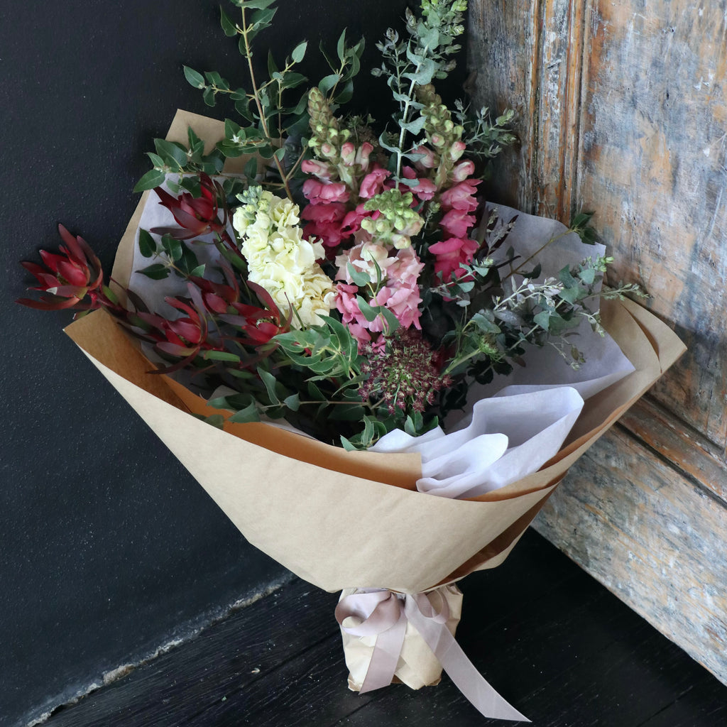 Winter tone floral arrangement wrapped in brown Kraft paper with white tissue designed by Bendigo Florist Blumetown.