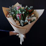 Load image into Gallery viewer, Native and Pastel flower mix with lush foliage Bendigo. Bouquet wrapped in brown paper with cream ribbon or offered in a vase. Billy buttons featured in arrangement. 
